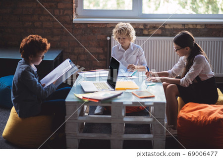 Three kids studying together and looking involved 69006477