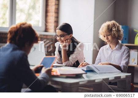 Three classmates sitting in the classroom and studying Three classmates sitting in the classroom and studying 69006517