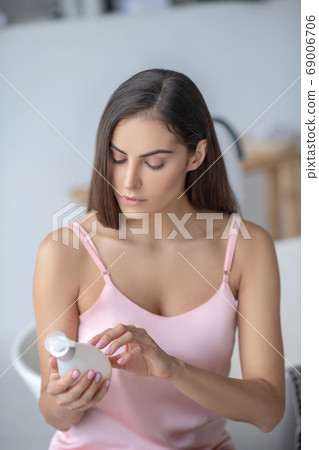 Pretty long-haired woman reading about new body lotion Pretty long-haired woman reading about new body lotion 69006706