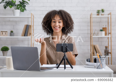 Modern hobby and blog concept. Happy woman looking at webcam sitting at table in interior 69006882