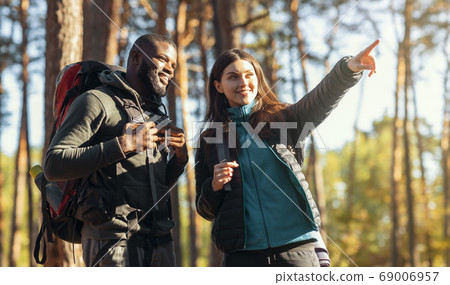 Mixed race couple of hikers walking by forest Mixed race couple of hikers walking by forest 69006957