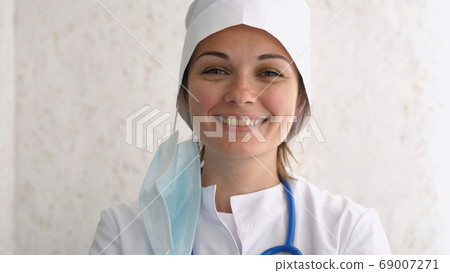 Portrait of a smiling female doctor with removed mask Portrait of a smiling female doctor with removed mask 69007271