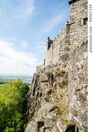 The walls of Stirling Castle, built on a rocky mountain outside Edinburgh, and the greenery and mountains in the distance 69007334