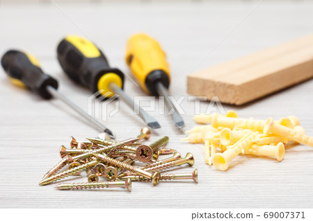 Screwdrivers, wooden block and screws on white 69007371