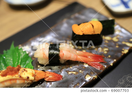 Shrimp sushi on a traditional Japanese plate in a Japanese restaurant. Selective focus. Shrimp sushi on a traditional Japanese plate in a Japanese restaurant. Selective focus. 69007703
