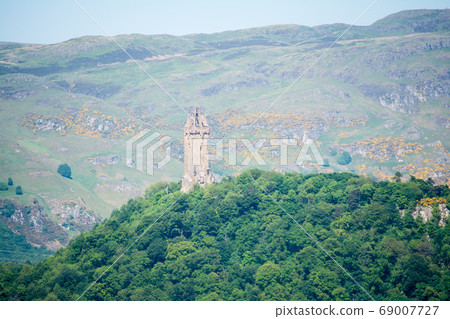 A historic stone tower on the hill, Wallace Monument and mountains near the Stirling Castle on the outskirts of Edinburgh A historic stone tower on the hill, Wallace Monument and mountains near the Stirling Castle on the outskirts of Edinburgh 69007727