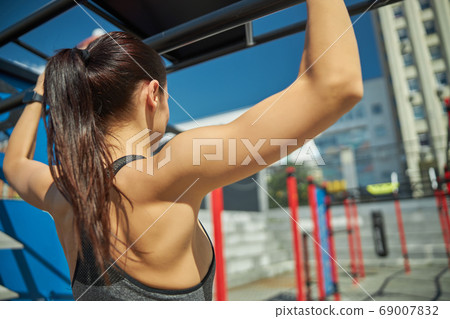 Serious longhaired brunette looking at sport equipment Serious longhaired brunette looking at sport equipment 69007832