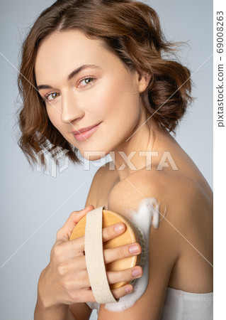 Beautiful dark-haired woman performing an exfoliation procedure Beautiful dark-haired woman performing an exfoliation procedure 69008263