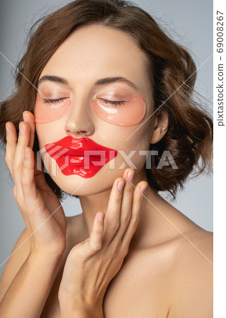 Woman using a collagen lip mask and under-eye patches Woman using a collagen lip mask and under-eye patches 69008267