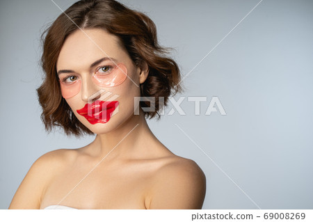 Female with a collagen lip mask and hydrogel eye patches Female with a collagen lip mask and hydrogel eye patches 69008269