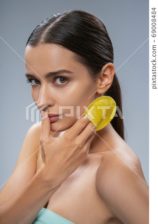 Serene dark-haired Caucasian lady touching her face 69008484