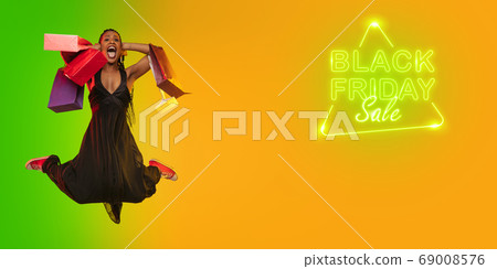 Portrait of young woman in neon light on gradient backgound. The human emotions, black friday, cyber monday, purchases, sales, finance concept. Neoned lettering. Portrait of young woman in neon light on gradient backgound. The human emotions, black friday, cyber monday, purchases, sales, finance concept. Neoned lettering. 69008576