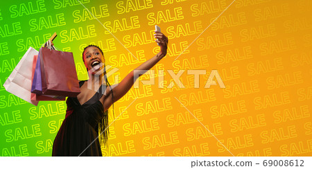 Portrait of young woman in neon light on gradient backgound. The human emotions, black friday, cyber monday, purchases, sales, finance concept. Neoned lettering. 69008612