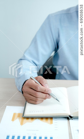 Businessman hand writting on notebook and analysis the chart with laptop at office 69008638
