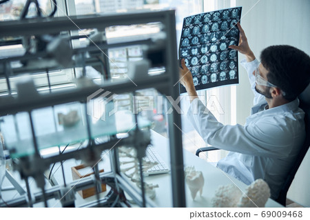 Scientist scrutinizing the magnetic resonance imaging of the head 69009468