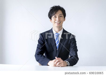 A young man in a suit smiling at the camera 69010065