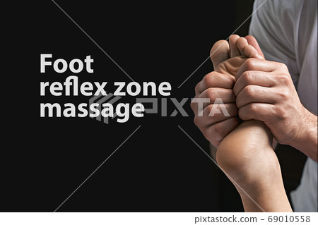 Male masseur hands doing reflexology massage on female foot reflex zones in the spa salon. Copy space with sample text. 69010558