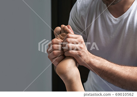 Male masseur hands doing reflexology massage on female foot reflex zones in the spa salon. 69010562