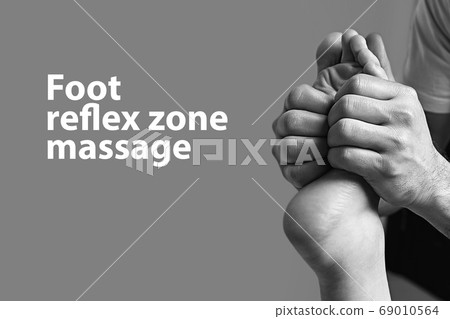 Male masseur doing massage on female foot reflex zone in the spa salon. Copy space with sample text on light grey background. 69010564