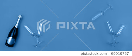 Champagne bottle and glasses on trendy blue background with place for text. Holiday concept. Mockup for your web banner design. Flat lay style. Champagne bottle and glasses on trendy blue background with place for text. Holiday concept. Mockup for your web banner design. Flat lay style. 69010767