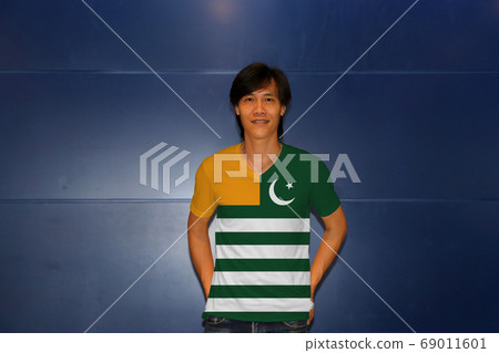 Man wearing Azad Kashmir flag on shirt and standing on the blue wall background. 69011601