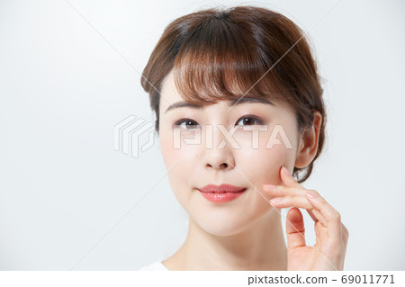 微笑用她的在她的面頰（白色背景）的手的一個少婦 69011771