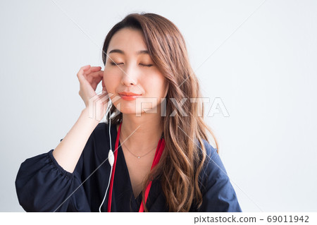 Woman listening to the sound of earphones Woman listening to the sound of earphones 69011942