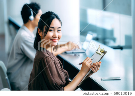 休閒服裝回答問卷的年輕女商人在辦公室 休閒服裝回答問卷的年輕女商人在辦公室 69013019