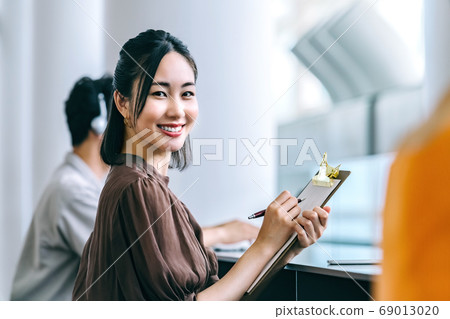 休閒服裝回答問卷的年輕女商人在辦公室 休閒服裝回答問卷的年輕女商人在辦公室 69013020