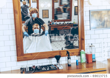 Man getting hair cut at the barbershop wearing mask during coronavirus pandemic Man getting hair cut at the barbershop wearing mask during coronavirus pandemic 69013715