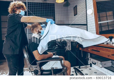 Man getting hair cut at the barbershop wearing mask during coronavirus pandemic Man getting hair cut at the barbershop wearing mask during coronavirus pandemic 69013716