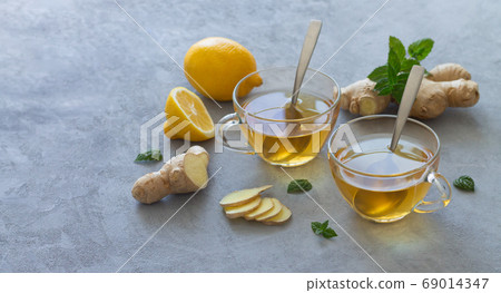 Two glass cups of ginger tea with lemons and mint leaves 69014347
