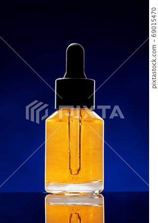 Glass bottle with cosmetic oil on dark background Glass bottle with cosmetic oil on dark background 69015470