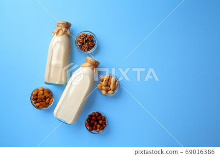 Bottles of vegan non dairy milk with various nuts on blue background 69016386