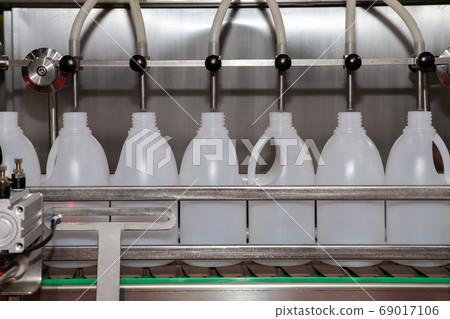 white plastic gallons or bottle on production line of conveyor at filling machine in factory. white plastic gallons or bottle on production line of conveyor at filling machine in factory. 69017106