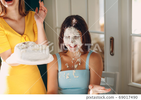 Young woman dip face in white cake with cream. Happy birthday concept. 69017490