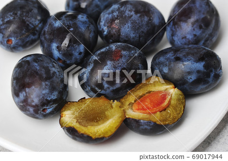 juicy ripe black and blue plums on a plate juicy ripe black and blue plums on a plate 69017944