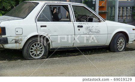 Old worn out and rusted abandoned car with flat 69019129