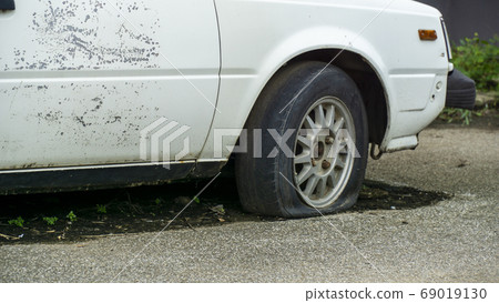 Old worn out and rusted abandoned car with flat 69019130