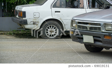 Old worn out and rusted abandoned car with flat 69019131