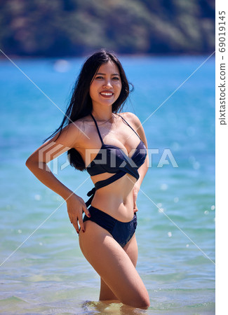 Beautiful asian woman posing on a tropical beach 69019145