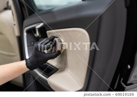 Man cleaning car leather interior with brush. Man cleaning car leather interior with brush. 69019189
