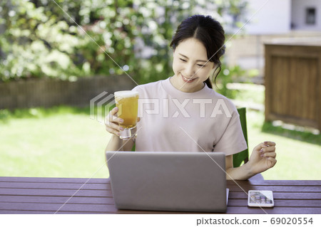 A young woman having an online drinking party on the terrace 69020554