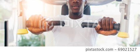 African American athlete doing exercise for chest muscles on pec deck machine during workout in gym African American athlete doing exercise for chest muscles on pec deck machine during workout in gym 69021527