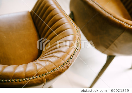 A close-up of the back of the chair, which turns into an armrest made of brown genuine leather. A close-up of the back of the chair, which turns into an armrest made of brown genuine leather. 69021829