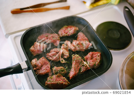 Four raw steaks are fried on a grilled pan. Four raw steaks are fried on a grilled pan. 69021854