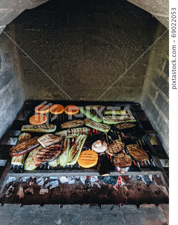 Grilled vegetables. Courgette, mushrooms and pumpkin on a metal grill over red coals. Grilled vegetables. Courgette, mushrooms and pumpkin on a metal grill over red coals. 69022053