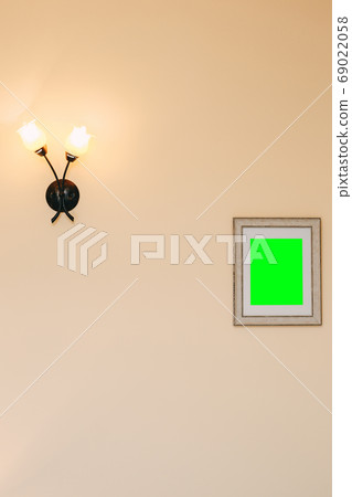 A framed painting with a green screen and a wall lamp in the form of two flowers. A framed painting with a green screen and a wall lamp in the form of two flowers. 69022058