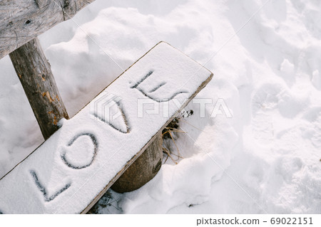 The lettering LOVE in the snow, on a wooden bench. The lettering LOVE in the snow, on a wooden bench. 69022151