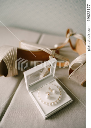 Mother-of-pearl women's sandals and a box with a bracelet of white beads and earrings. Mother-of-pearl women's sandals and a box with a bracelet of white beads and earrings. 69022177